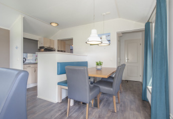 Dining area at Stern 6 lodge in Giethoorn, Netherlands, featuring blue bench, table, and modern decor.