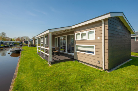 Modernes Ferienhaus am Wasser in Giethoorn, Niederlande, mit Terrasse, Rasen und Boot am Kanal.