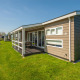 Modernes Ferienhaus am Wasser in Giethoorn, Niederlande, mit Terrasse, Rasen und Boot am Kanal.