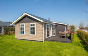 Udendørs billede af Stern 6 hytte i Giethoorn, Holland, med grøn græsplæne og terrasse med havemøbler.