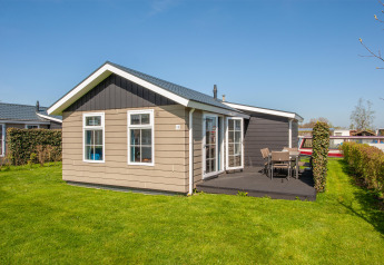 Exterior view of Stern 6 lodge in Giethoorn, Netherlands, featuring a patio, garden chairs and a green lawn.