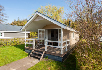 Tiny House 2 features a cozy porch with white railings and garden views, surrounded by greenery.