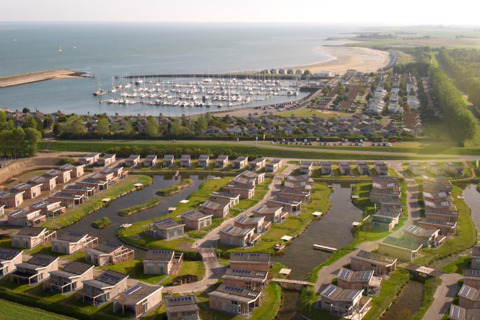 Luftaufnahme vom Water Village Ferienpark in Zeeland, Niederlande, mit modernen Häusern und Jachthafen am Meer.