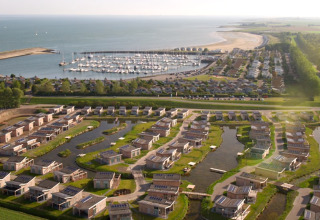 Vista aérea de Water Village, un parque vacacional en Zelanda, Países Bajos, con villas modernas y puerto deportivo.