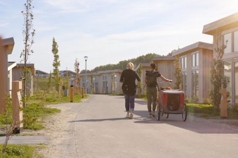 Zwei Menschen spazieren durch den Water Village Ferienpark in Zeeland, Niederlande, bei Sonnenschein.