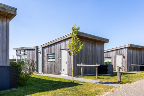 Moderne, træbeklædte hytter på Lodge 4 ved Water Village i Holland under en klar blå himmel.