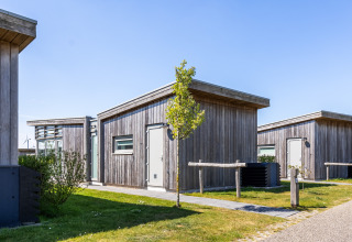 Moderne Holzhütten von Lodge 4 im Water Village, Niederlande, bei sonnigem, klarem Himmel.