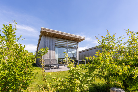 Buitenzicht van Lodge 4 in Water Village, Nederland, modern houten huisje met terras en tuin.