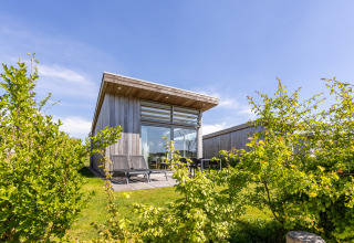 Außenansicht der Lodge 4 im Water Village, Niederlande, modernes Holzhaus mit Terrasse und Garten.