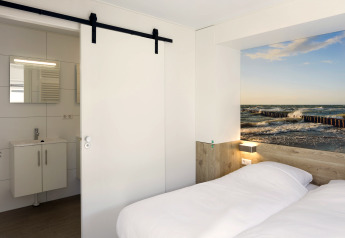 Schlafzimmer in Lodge 4 im Water Village, Niederlande, mit Doppelbett, Bad und Meeresbild an der Wand.