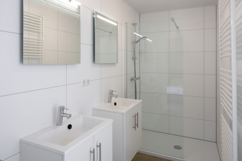 Modernes Badezimmer in Lodge 4 im Water Village, Niederlande, mit zwei Waschbecken und großer Dusche.
