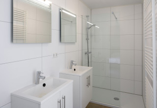 Moderne badkamer in Lodge 4 van Water Village, Nederland, met dubbele wastafels en ruime douche.