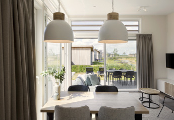 Eetkamer in moderne lodge met pendelverlichting en uitzicht op terras en tuin in Water Village, Nederland.