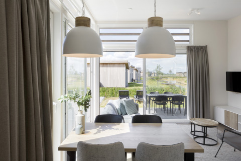 Eetkamer in moderne lodge met pendelverlichting en uitzicht op terras en tuin in Water Village, Nederland.