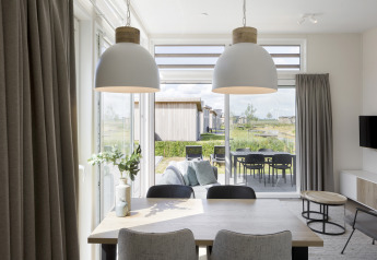 Moderne lodge med spisebord, loftslamper og udsigt til terrasse og have i Water Village, Holland.