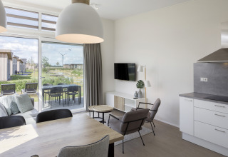 Modernes Wohnzimmer in Lodge 4, Water Village, Niederlande, mit Blick auf Terrasse und grüne Umgebung.