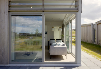 Blick durch große Fenster auf ein modernes Wohnzimmer in Lodge 4 im Water Village, Niederlande, mit Natur außen.