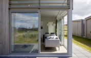 Blick durch große Fenster auf ein modernes Wohnzimmer in Lodge 4 im Water Village, Niederlande, mit Natur außen.