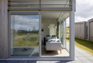 Blick durch große Fenster auf ein modernes Wohnzimmer in Lodge 4 im Water Village, Niederlande, mit Natur außen.
