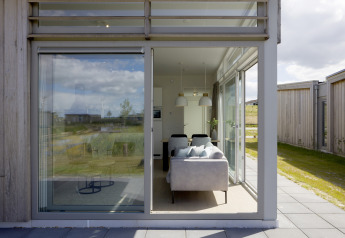 Udsigt gennem store vinduer til en moderne stue i Lodge 4, Water Village, Nederlandene, med natur udenfor.