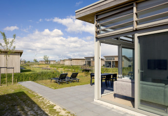 Lodge 4 in Water Village in Nederland, met grote ramen, terras, ligzetels en zicht op andere chalets.