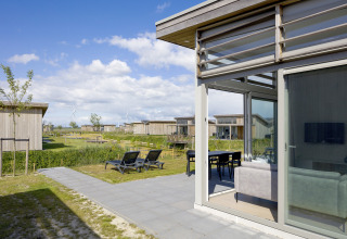 Lodge 4 in Water Village in Nederland, met grote ramen, terras, ligzetels en zicht op andere chalets.