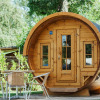 Barrel-shaped wooden glamping pod at Camping Gugel – Pods Baden-Württemberg, set among green trees.