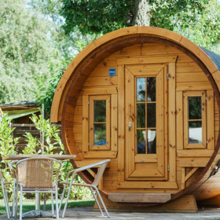 Barrel-shaped wooden glamping pod at Camping Gugel – Pods Baden-Württemberg, set among green trees.