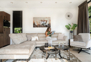 Vrouw leest in moderne woonkamer met lichte bank in Villa Bloomingdale bij MarinaPark Residentie Bloemendaal, Nederland.