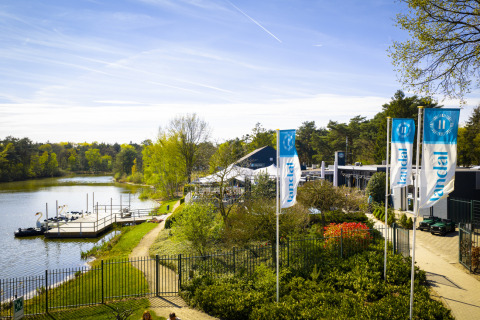 Udsigt over søen og ferieparken Bospark 't Wolfsven i North-Brabant, Holland, med svanebåde og flag.