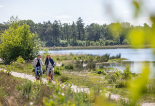 Twee mensen fietsen langs een meer op een natuurpad in de omgeving van Mierlo, Noord-Brabant, Nederland.