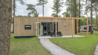 Udendørsbillede af Timber Cottage 4, et moderne tiny house med træfacade og terrasse i grønne omgivelser.