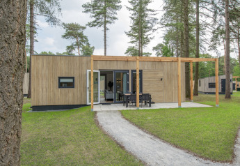 Udendørsbillede af Timber Cottage 4, et moderne tiny house med træfacade og terrasse i grønne omgivelser.