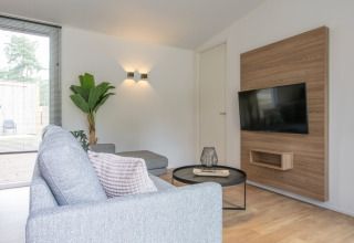 Soggiorno moderno in Timber Cottage 4 al Bospark 't Wolfsven, Paesi Bassi, con divano e TV.