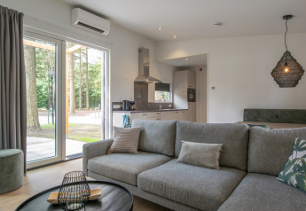 Wohnbereich und Küche im Timber Cottage 4, Bospark 't Wolfsven, mit Blick nach draußen in die Natur.