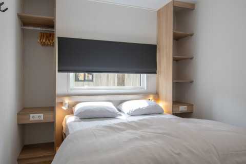 Schlafzimmer mit Doppelbett in einem Tiny House namens Timber Cottage 6 im Bospark 't Wolfsven, Niederlande.
