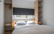 Bedroom with double bed in Timber Cottage 6, a tiny house at Bospark 't Wolfsven in the Netherlands.