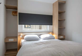 Chambre avec lit double dans Timber Cottage 6, une tiny house à Bospark 't Wolfsven, Pays-Bas.