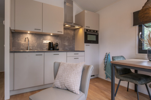 Cucina moderna e compatta e area pranzo in Tiny House 2 a Bospark 't Wolfsven, Paesi Bassi.