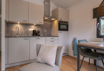 Cucina moderna e compatta e area pranzo in Tiny House 2 a Bospark 't Wolfsven, Paesi Bassi.