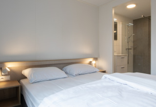 Camera da letto in Tiny House 2 al Bospark 't Wolfsven nei Paesi Bassi con letto matrimoniale e bagno.