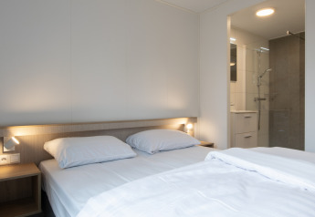 Dormitorio en Tiny House 2 en Bospark 't Wolfsven, Países Bajos, con cama doble y baño moderno.
