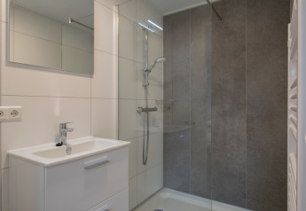 Modernes Bad im Tiny House 2 im Bospark 't Wolfsven, Niederlande, mit Dusche und Waschbecken.
