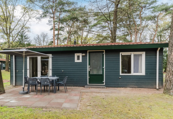 Chalet WVR6 en Bospark 't Wolfsven, con patio, mesa exterior y sombrilla rodeado de árboles y naturaleza.
