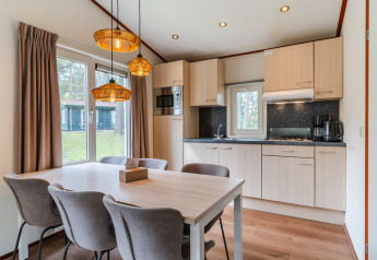 Moderne køkken og spiseområde i chalet WVR6 på Bospark 't Wolfsven, Nederlandene, med store vinduer og træinteriør.