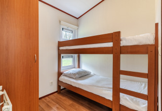 Small bedroom in chalet WVR6 at Bospark 't Wolfsven, Netherlands, featuring bunk beds and wood floor.
