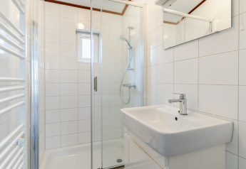 Baño moderno con ducha, lavabo blanco y espejo en el chalet WVR6 de Bospark 't Wolfsven, Países Bajos.
