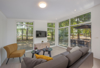 Living room in Lodge 6 at Bospark 't Wolfsven, Netherlands, with modern furniture and forest views.