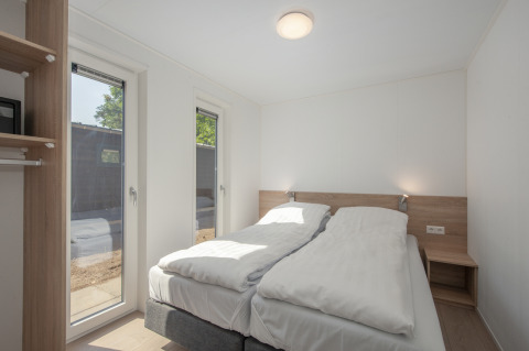 Bright bedroom in Lodge 6 at Bospark 't Wolfsven, Netherlands, featuring twin beds and large windows.