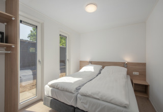 Bright bedroom in Lodge 6 at Bospark 't Wolfsven, Netherlands, featuring twin beds and large windows.